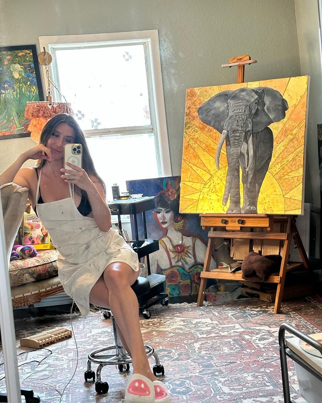 Taylor Christine in her studio beside a gold elephant painting on the easel